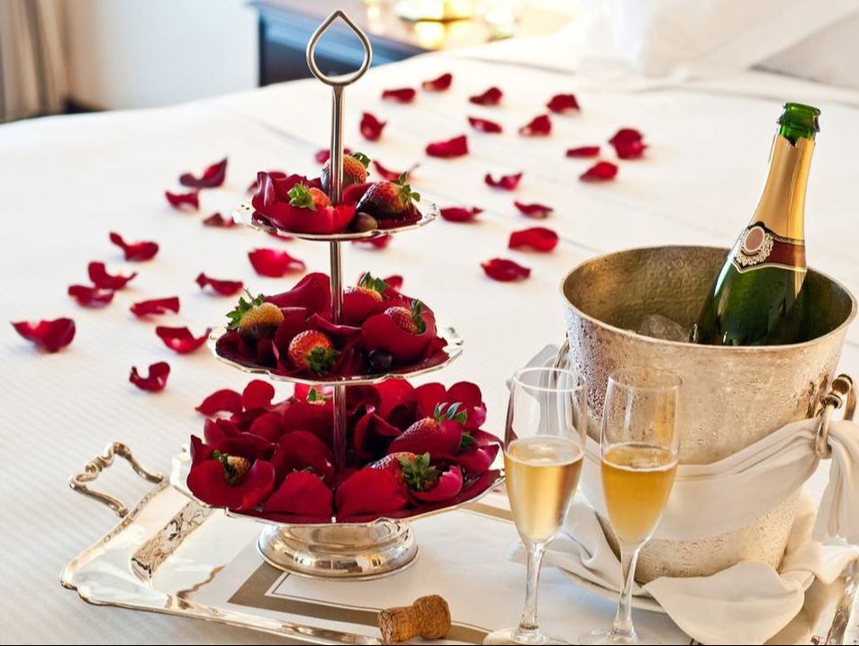 Strawberrries, champagne, and rose petals on bridal bed